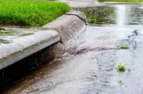 Stormwater flowing into street intake drain after a storm